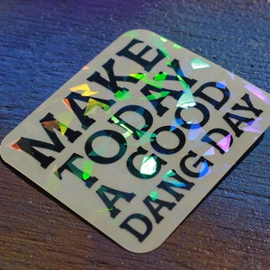 May include: A white sticker with a holographic finish and black text that reads "Make Today A Good Dang Day".