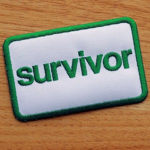 May include: A white patch with a green border and the word "survivor" embroidered in green.