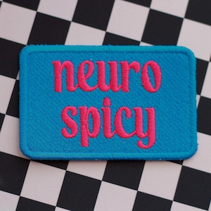 May include: A blue fabric patch with pink embroidered text that reads "neuro spicy".