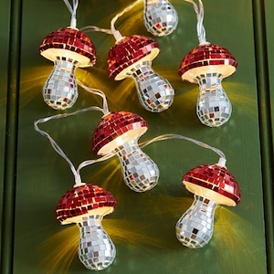 May include: A string of decorative lights featuring mushroom-shaped ornaments covered in small, reflective mirror tiles. The mushroom caps are composed of red mirror tiles, while the stems are made of silver mirror tiles, emitting a warm glow.