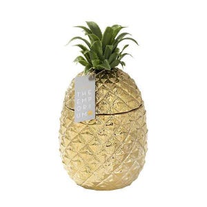 Op de afbeelding: Een gouden ananasvormige container met een groene ananas bovenkant. De container heeft een label met de tekst "The Emporium".