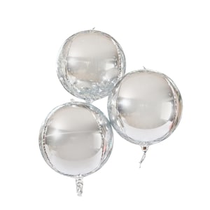 Puede incluir: Tres globos esféricos plateados. Cada globo es redondo con una superficie reflectante, creando un efecto de espejo. Los globos están agrupados, con sus extremos atados visibles en la parte inferior. Los globos están inflados y listos para una fiesta.