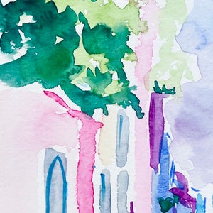 以下が含まれることがあります： ピンク、イエロー、ブルーの建物を描いた水彩画。建物の前に緑の木がある。