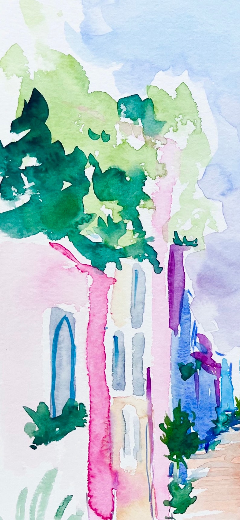以下が含まれることがあります： ピンク、イエロー、ブルーの建物を描いた水彩画。建物の前に緑の木がある。