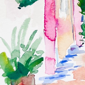 以下が含まれることがあります： ピンクの建物を描いた水彩画。窓は青と黄色。手前に緑の植物がある。右下に「julia」という署名がある。