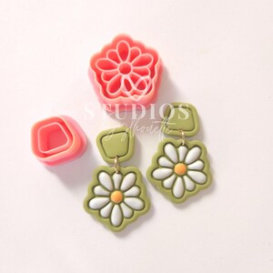 May include: A set of polymer clay earring molds featuring a daisy flower and a square shape. The molds are pink and are shown with green and white polymer clay earrings.