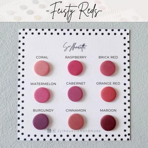 Pode incluir: Uma carta de cores com 10 tons diferentes de vermelho, etiquetados com nomes como Coral, Framboesa, Vermelho tijolo, Melancia, Cabernet, Vermelho laranja, Borgonha, Canela e Marrom. A carta &eacute; intitulada "Feisty Reds" e tem o texto "Sylhouette Handmade" na parte inferior.