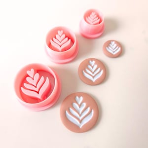 May include: Set of four pink and brown cookie cutters and fondant stamps featuring a leaf design. The cutters are different sizes and the stamps are brown with white leaf designs.