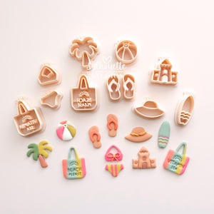 May include: A collection of light peach-coloured plastic cookie cutters and corresponding colourful clay shapes featuring beach themes including palm trees, beach balls, sandcastles, flip-flops, tote bags with text reading Beach Please or Vitamin Sea, hats, and surfboards.