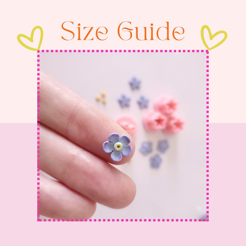 May include: A close-up of a finger holding a small purple flower with a yellow center. The flower is surrounded by other small flowers in various colors, including pink and purple.
