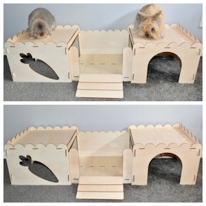 May include: A wooden rabbit hutch with two levels, a ramp, and a carrot cutout. The hutch is made of natural wood and has a scalloped edge. Two rabbits are sitting on the top level of the hutch.