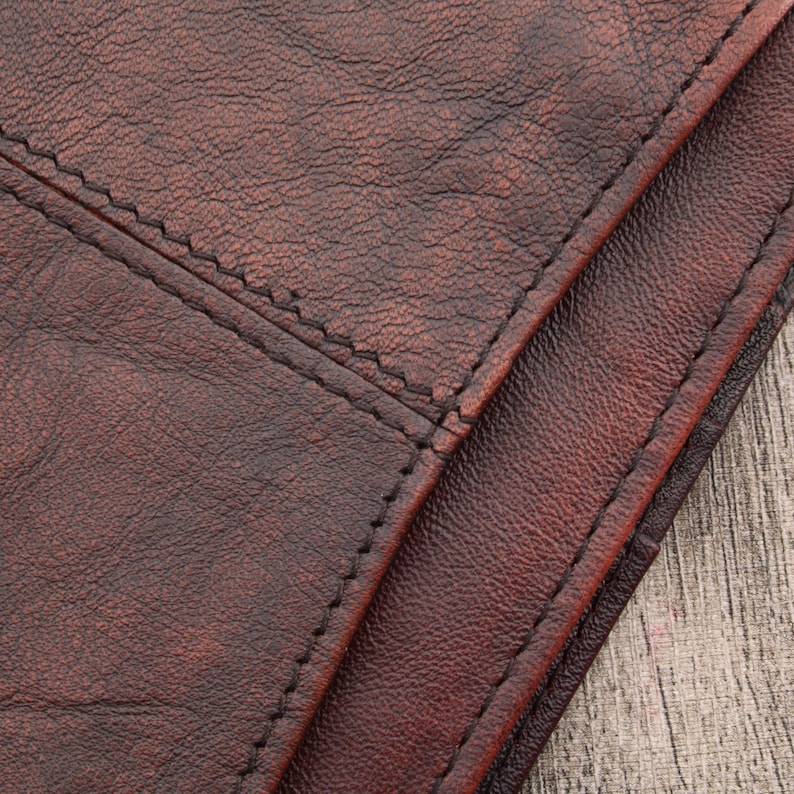 May include: Close-up of brown leather with a stitched seam. The leather has a textured surface.