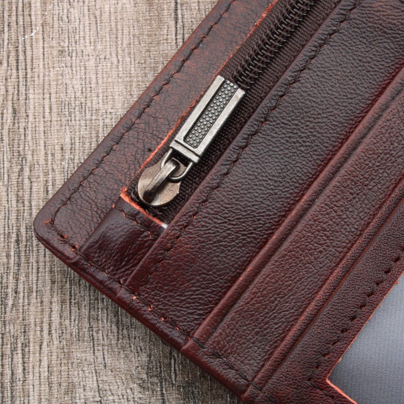 May include: A brown leather wallet with a zippered pocket and a silver zipper pull.