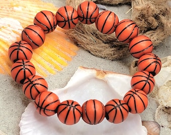 Könnte beinhalten: Ein Armband aus orangefarbenen, basketballförmigen Perlen. Die Perlen sind auf einer durchsichtigen Gummikordel aufgefädelt.
