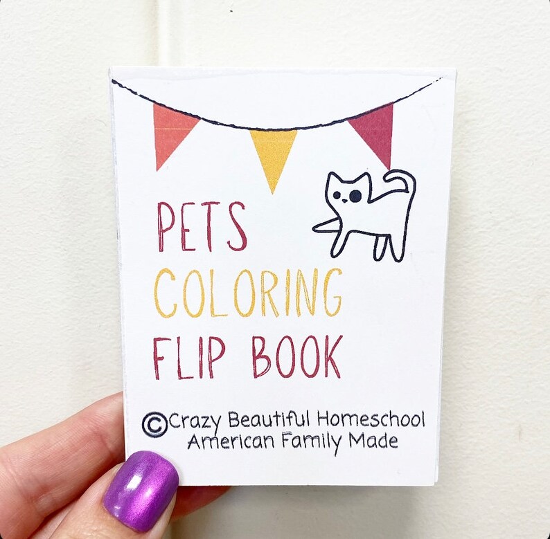 May include: A white flip book with a red, yellow, and white bunting at the top. The book says "Pets Coloring Flip Book" in black and yellow text. A white cat with black eyes is drawn on the front. The copyright information at the bottom reads "&copy;Crazy Beautiful Homeschool American Family Made".