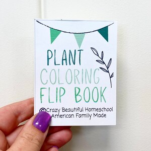 May include: A white card with green and black text that reads "PLANT COLORING FLIP BOOK" with a green and black leaf design and a string of green flags. The text at the bottom reads "Crazy Beautiful Homeschool American Family Made".