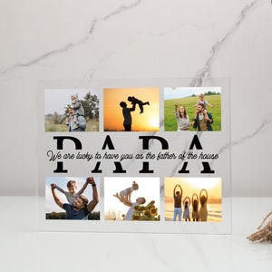 May include: A clear acrylic photo frame with a collage of family photos. The frame has the word "PAPA" in black letters and the text "We are lucky to have you as the father of the house".
