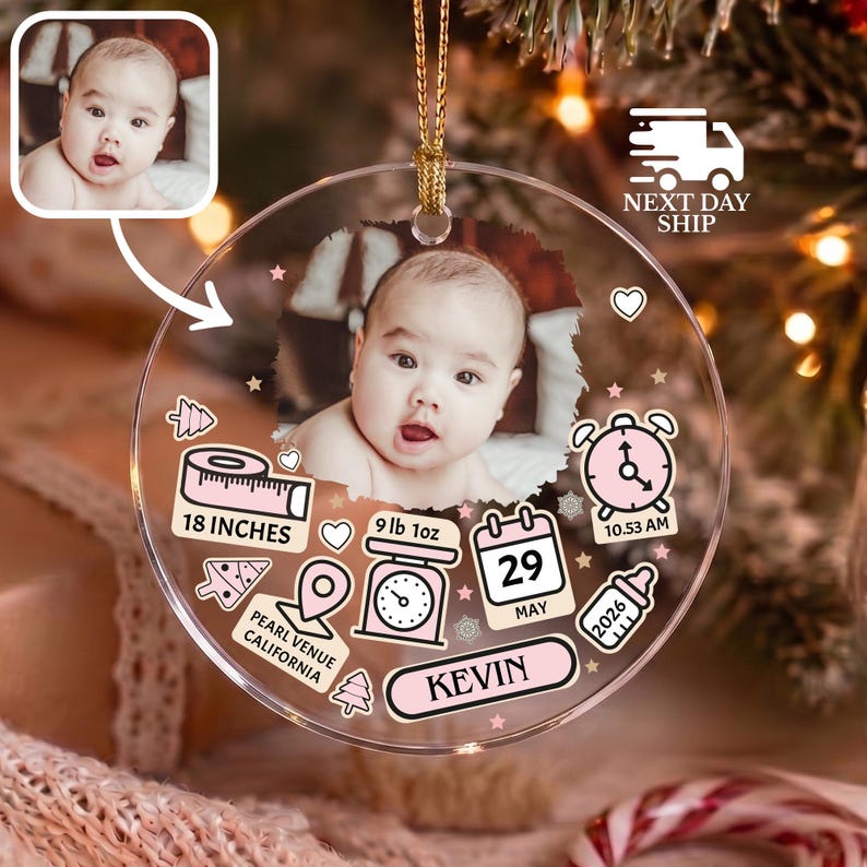 K&ouml;nnte beinhalten: Ein rundes, transparentes Acryl-Ornament mit einem zentralen Babyfoto. Die aufgedruckten Grafiken zeigen ein rosa Ma&szlig;band mit der Aufschrift 18 INCHES, eine Waage mit 9 lb 1oz, einen Kalender mit 29 MAY, eine Uhr auf 10.53 AM, eine Flasche und den Namen KEVIN.