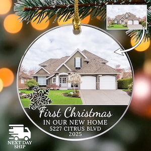 May include: Clear, round Christmas ornament with a house photo inside. The ornament has the text "First Christmas In Our New Home 5227 Citrus Blvd 2025". A snowflake design is on the left side. A small image of the house is in the upper right.