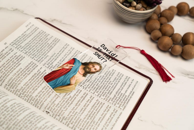 May include: A clear plastic bookmark with a picture of Jesus Christ and the text "David! Is That SMUT?" printed on it. The bookmark has a red tassel.