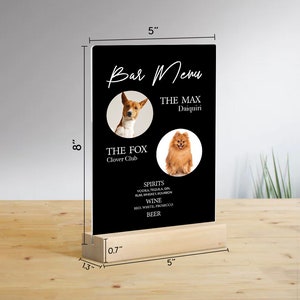 May include: Black acrylic sign with a wooden base, measuring 8 inches tall and 5 inches wide. The sign features a bar menu with two dog photos and the text "Bar Menu", "The Max Daiquiri", "The Fox Clover Club", "Spirits", "Vodka, Tequila, Gin, Rum, Whiskey, Bourbon", "Wine", "Red, White, Prosecco", and "Beer".