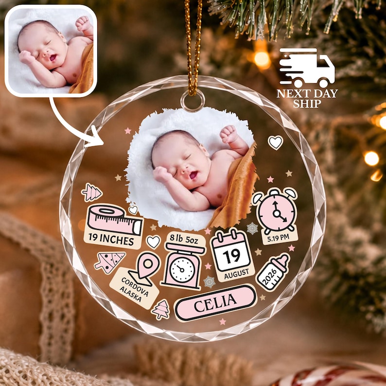 May include: A round, faceted glass ornament featuring a central photograph of a sleeping baby. The design includes pink icons of a measuring tape labeled 19 INCHES, a scale labeled 8 lb 5oz, a calendar showing 19 AUGUST, a clock, a bottle, and text reading CORDOVA ALASKA and CELIA.