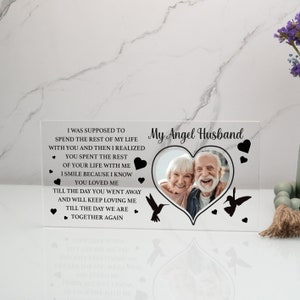 May include: A clear acrylic memorial plaque with a heart-shaped photo frame and the text "My Angel Husband". The plaque features a black and white photo of an older couple smiling. The text reads "I was supposed to spend the rest of my life with you and then I realized you spent the rest of your life with me. I smile because I know you loved me. Till the day you went away and will keep loving me. Till the day we are together again."