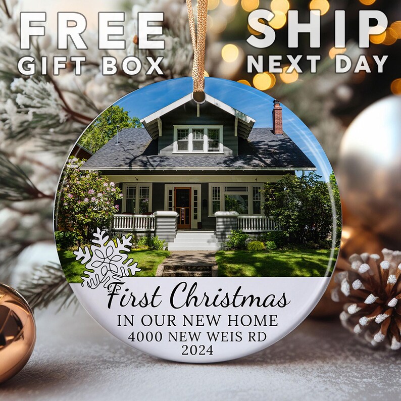 May include: Round Christmas ornament featuring a house with a gray exterior and white trim. The ornament has the text "First Christmas In Our New Home 4000 NEW WEIS RD 2024". A gold string is attached for hanging. The words "FREE GIFT BOX" and "SHIP NEXT DAY" are also visible.