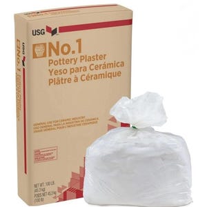 May include: A tan cardboard box labeled USG No.1 Pottery Plaster with text in English, Spanish, and French, alongside a clear plastic bag filled with white powder. The box indicates a net weight of 100 lb or 45.3 kg for the ceramic material.