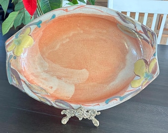 Oval hand-painted ceramic bowl or platter, likely in the majolica style. It features a vibrant peach or orange luster interior glaze.
