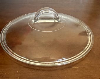 Vintage Pyrex L-22-C clear glass replacement lid with a distinctive half-moon / fin arched handle.