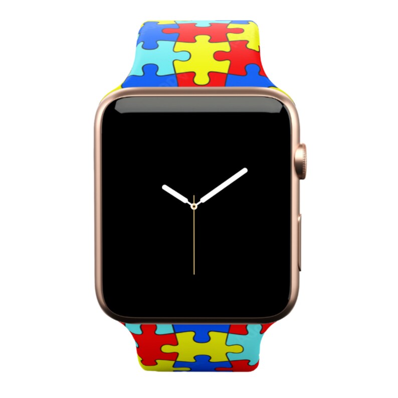 Puede incluir: Un Apple Watch dorado con una esfera negra y una banda con estampado de piezas de rompecabezas de colores. La banda es azul, amarilla y roja.