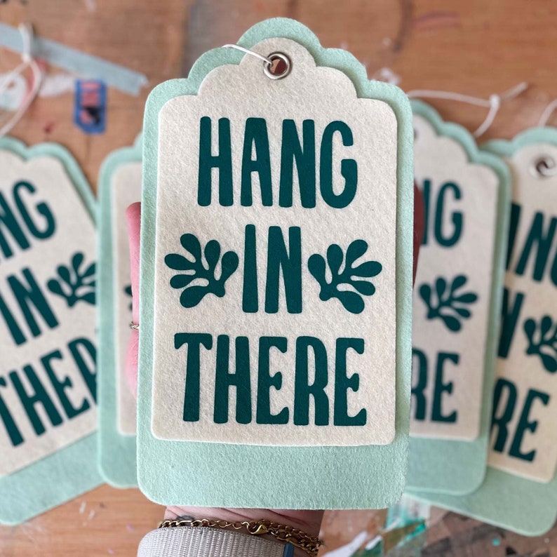 K&ouml;nnte beinhalten: Ein Set aus drei gr&uuml;nen und wei&szlig;en Filz-Geschenk-Etiketten mit dem Text "Hang in there" und einem Blatt-Design.