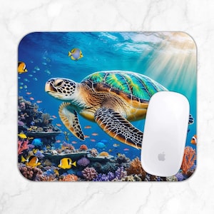 May include: A colorful mouse pad featuring a green sea turtle swimming through a vibrant coral reef with colorful fish. The turtle has a green, brown, and black shell and is swimming in blue water.