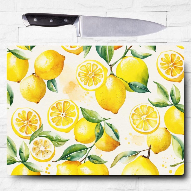 May include: A white cutting board with a watercolor pattern of lemons and leaves. The lemons are yellow and the leaves are green. The background is white with a few yellow watercolor splatters.