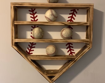 May include: A wooden baseball-shaped shelf with three shelves to display baseballs. The shelf is painted white with red stitching details. Five baseballs are displayed on the shelves.
