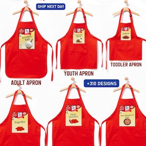 May include: Red aprons with various spice labels, including pepper, cinnamon sticks, and basil. The aprons are available in adult, youth, and toddler sizes. The image also includes text that says "+310 Designs".
