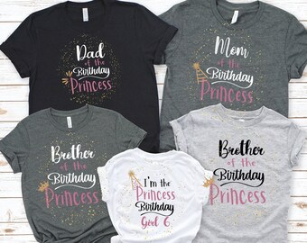 May include: Set of five t-shirts with a princess birthday theme. The shirts are in black, grey, and white. The text on the shirts reads "Dad of the Birthday Princess", "Mom of the Birthday Princess", "Brother of the Birthday Princess", "Brother of the Birthday Princess", and "I'm the Princess Birthday Girl 6".