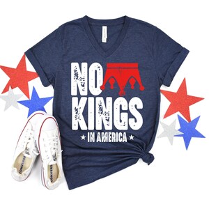 a navy blue t-shirt with the text "NO KINGS IN AMERICA" printed on it, along with a pair of white sneakers and red, white, and blue stars.
