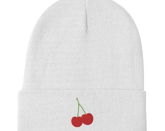 May include: White knitted beanie with a red cherry embroidered on the front.