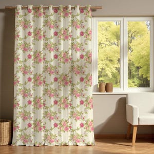 Könnte beinhalten: Cremefarbener Blumenvorhang mit einem sich wiederholenden Muster aus rosa Rosen und grünen Blättern. Der Vorhang hängt an einer Holzstange über einem Fenster mit Blick auf eine grüne Landschaft.