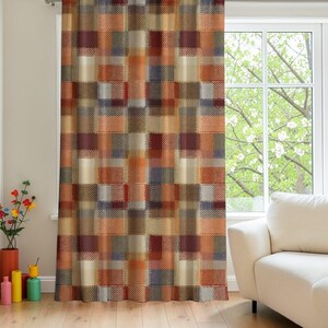 Peut inclure: Un rideau pleine longueur présentant un motif géométrique répétitif de blocs rectangulaires dans des tons orange, marron, crème et bleu foncé. Le design intègre une fine texture en pointillés sur toute la surface, créant un effet superposé.