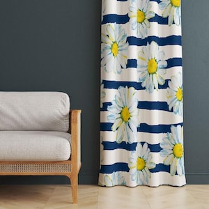 May include: A white and navy blue striped curtain with large daisy floral pattern. The daisies have white petals and yellow centers. The curtain is hanging in front of a dark blue wall.