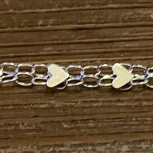 May include: A silver chain bracelet with small white heart charms.
