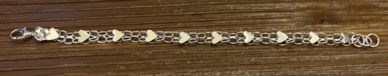 May include: A silver chain bracelet with small white heart charms.