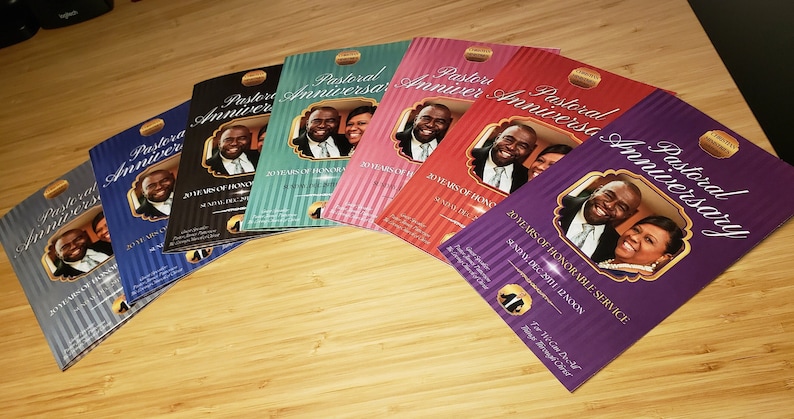 Puede incluir: Una pila de folletos de color morado, rojo, verde azulado, azul y gris con un borde dorado y una foto de una pareja en la portada. El texto en la portada de los folletos dice "Aniversario Pastoral" y "20 a&ntilde;os de servicio honorable".
