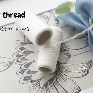 May include: Two spools of white thread for making bows, with the text "Bow thread" and "For faster bows" above them. A blue and green ribbon bow is in the background.