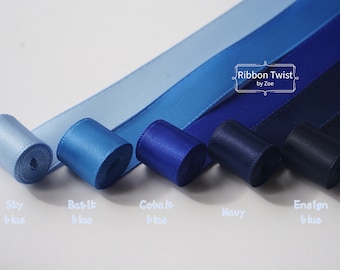 May include: Five spools of satin ribbon in shades of blue, from light sky blue to dark navy blue. The spools are labeled "Sky Blue", "Batik Blue", "Cobalt Blue", "Navy", and "Ensign Blue". The text "Ribbon Twist by Zoe" is printed on a white label.