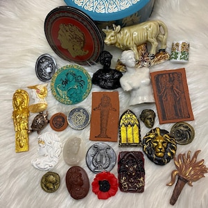 May include: A collection of vintage and antique decorative items, including a ceramic cow figurine, a round tin box with a blue and white floral design, a gold-colored angel figurine, a silver-colored lyre, a red poppy, and a variety of other small decorative items.