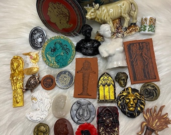 May include: A collection of vintage and antique decorative items, including a ceramic cow figurine, a round tin box with a blue and white floral design, a gold-colored angel figurine, a silver-colored lyre, a red poppy, and a variety of other small decorative items.